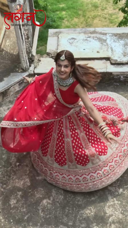 A bride seated with her red and white lehenga spread around her