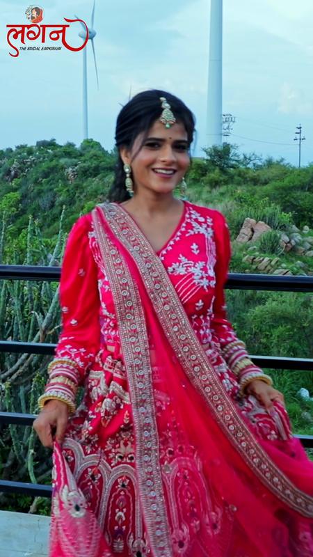 A bride in a red lehenga on a green hillside