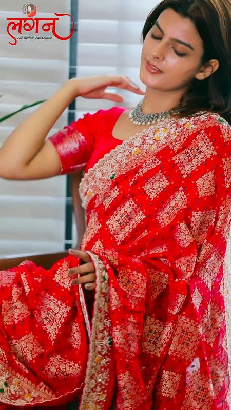 A red bandhej saree with an embroidered border